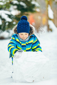 小可爱男孩做雪人滚大雪图片