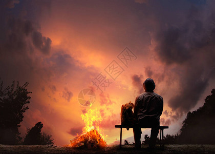 一名男旅行者背着包坐在营火附近日图片