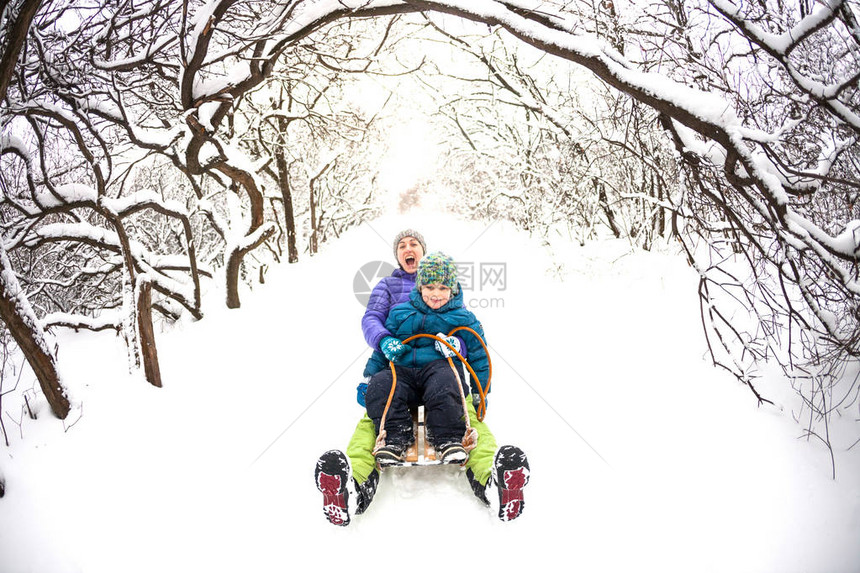 一个女人带着她的儿子骑着雪橇下山图片