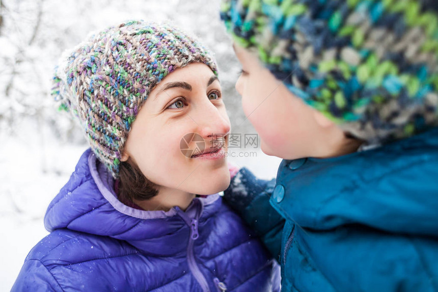 一个带着孩子的女人的画像男孩和他的母亲在冬天白雪覆盖的森林的背景下宝看着妈针织帽子冬季散步图片