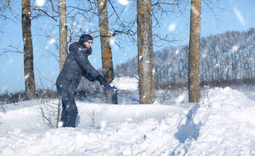 冬日男子用铲子从路上除雪图片