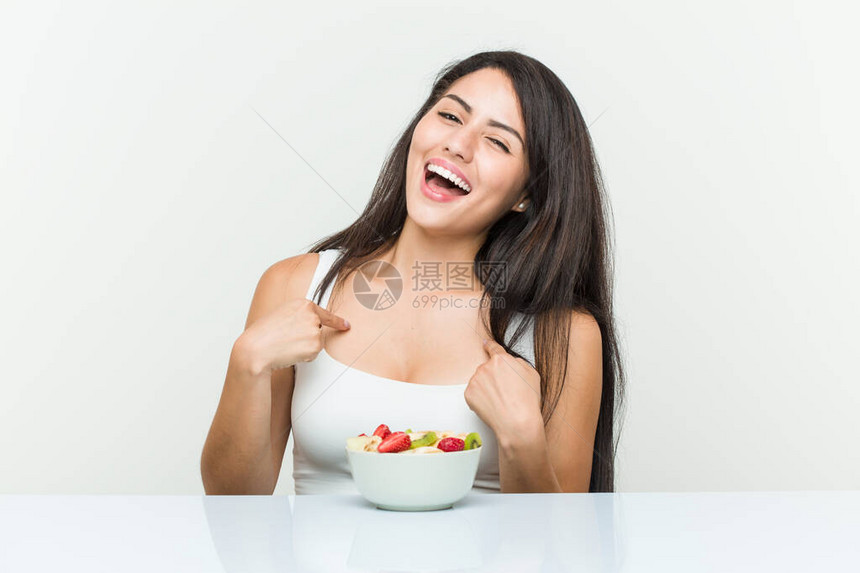 年轻的西班牙女人吃水果碗惊讶地指着自己图片