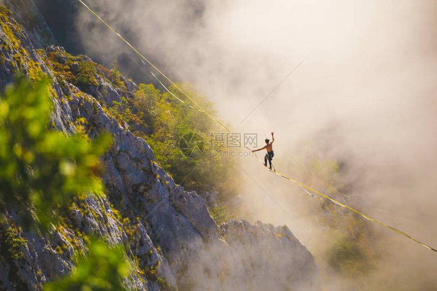 一个人沿着高在云层上方的拉长吊索行走highliner在峡谷中通过长而高的吊索拉力来保持平衡波斯尼亚和黑萨哥维那图片