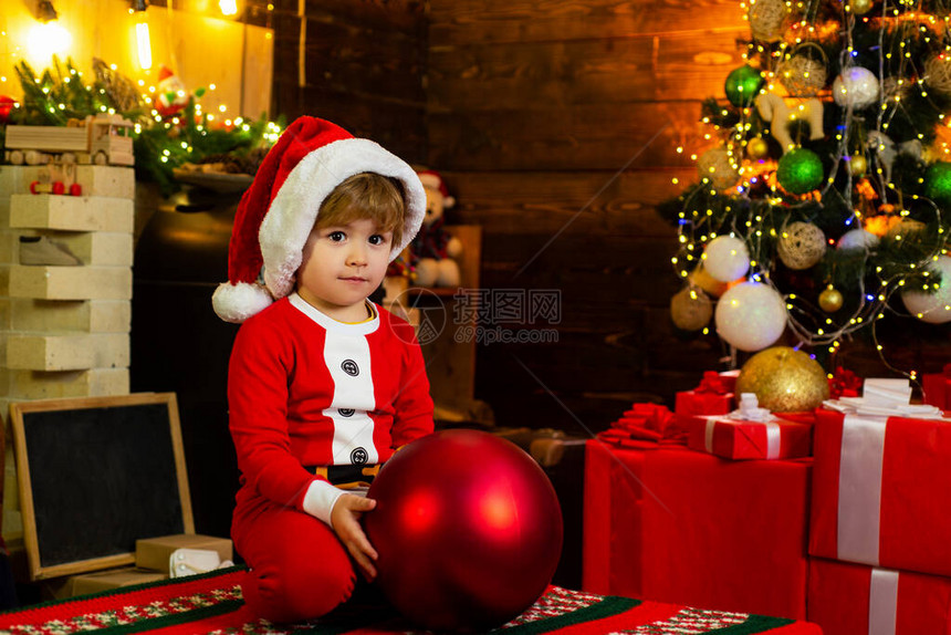 有圣诞树装饰球的小男孩今盒山新年快乐圣诞节前夕圣诞树和壁炉旁的孩图片