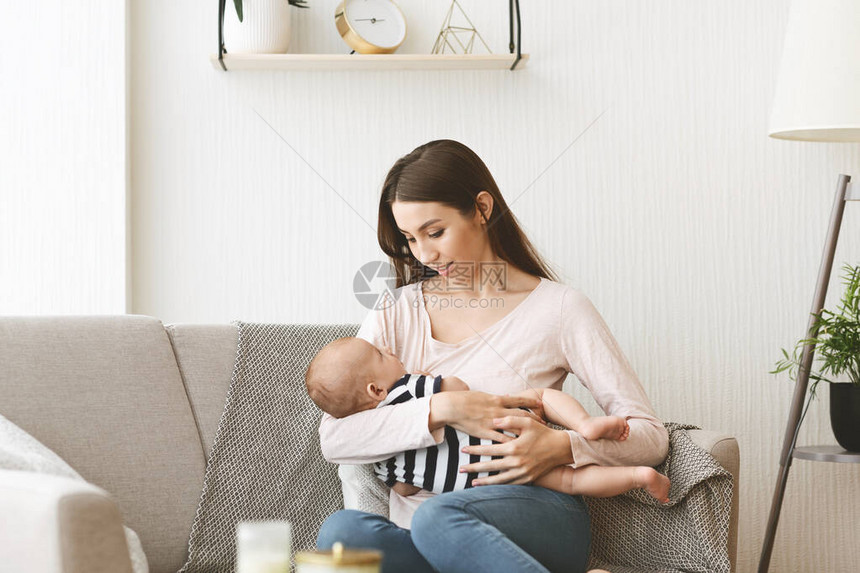 年轻母亲在家沙发上给新生婴儿喂奶图片