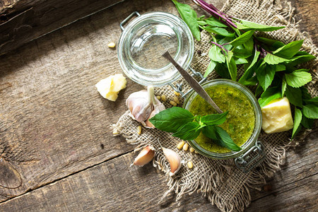 健康的意大利美食绿色香蒜酱与质朴的木桌上的成分平躺的顶视图您的文图片
