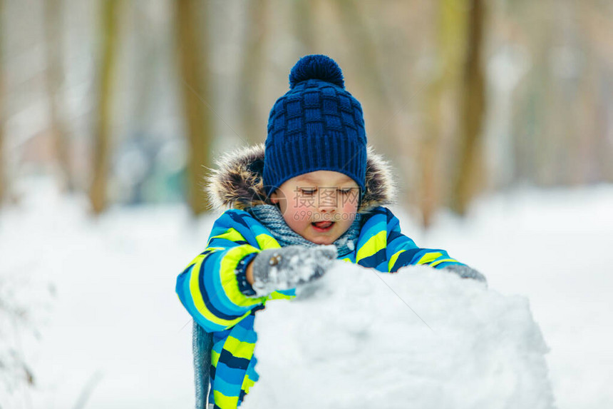 小可爱男孩做雪人滚大雪图片