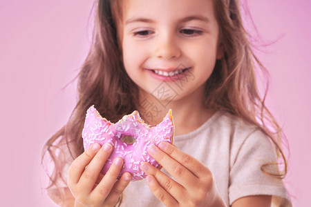 快乐的小女孩吃粉红甜圈图片