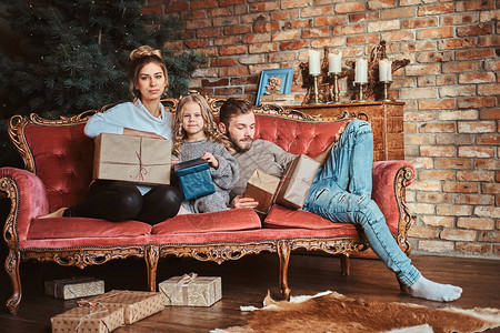 年轻的小家庭在红旧沙发上寒冷图片