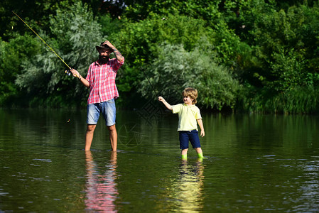 父亲和儿子钓鱼父亲和他的儿子在河边拿着钓图片