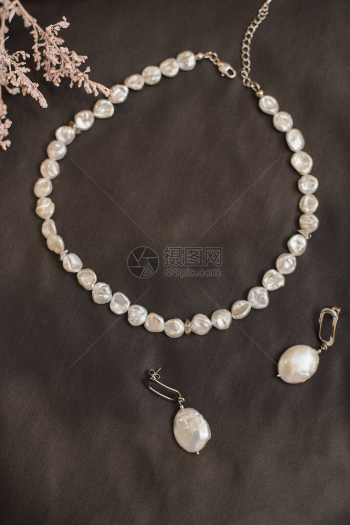 棕色皮革背景的珍珠项链和耳环图片