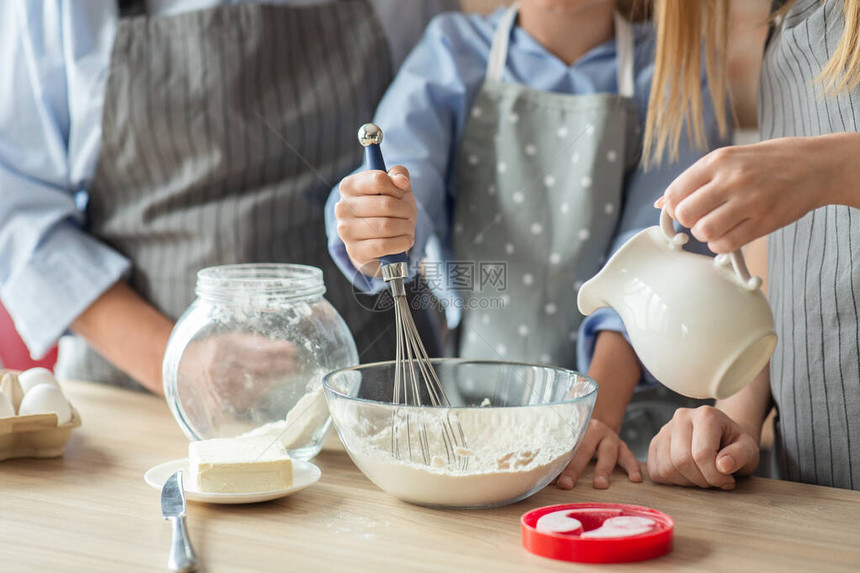 女孩学习如何烹饪与母亲和奶一起挣钱在厨房内做图片