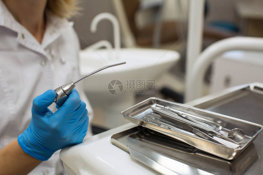 牙科医生的女牙医手在牙科诊所握有牙图片