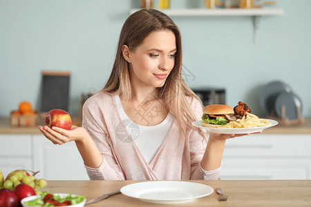 女人在厨房里选择健康和不健康的食图片