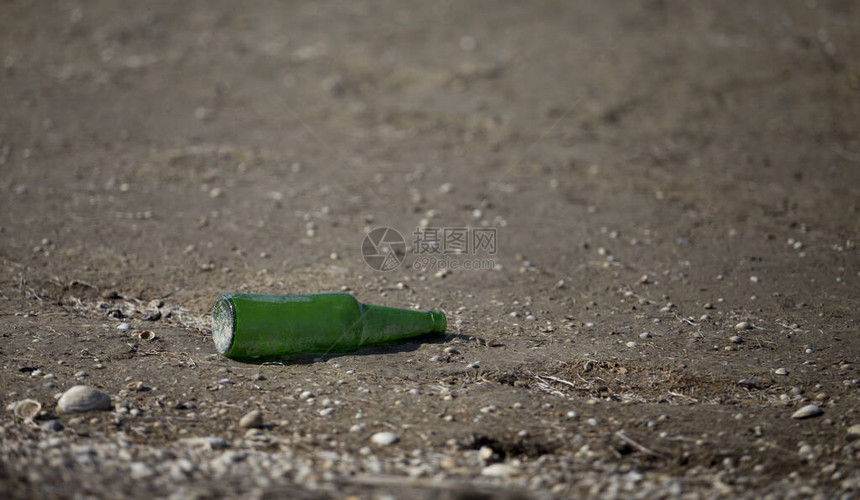 人类海滩污染低潮后在海边的玻璃啤酒图片
