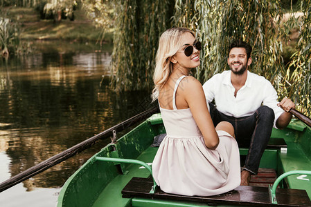 快乐的年轻女子在欢乐的男朋友身边坐船图片