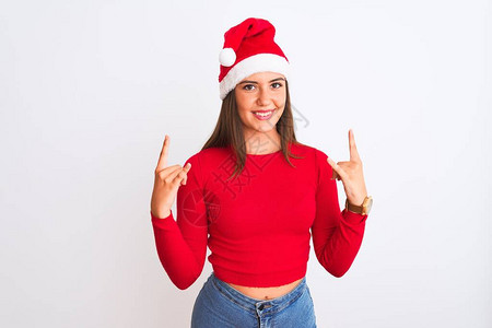 年轻漂亮的女孩戴着圣诞老人的帽子站在孤立的白色背景上图片