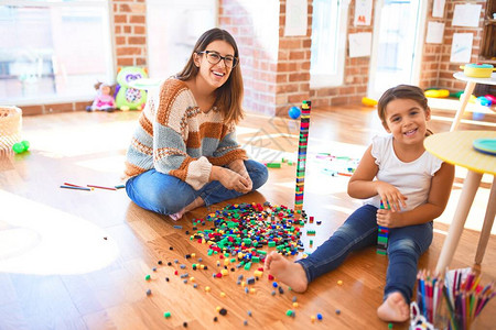 漂亮的老师和幼儿在幼儿园的许多玩具周图片