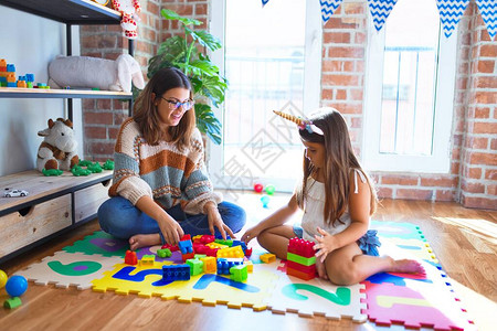 漂亮的老师和幼儿在幼儿园的许多玩具周图片