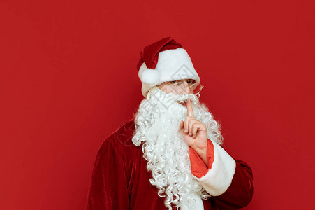严肃的圣诞老人在红色背景上表现出沉默的姿态图片