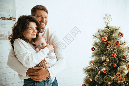 幸福的男子拥抱妻子和婴儿同时站图片
