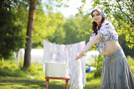 孕妇把洗好的衣服挂在绳子上晾干图片