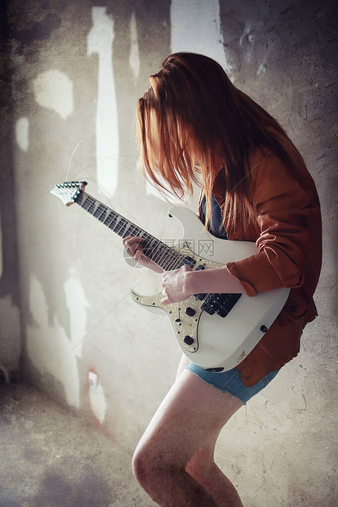 有电吉他的年轻红发女孩穿着皮夹克的摇滚音乐家女孩她是一个漂亮的歌手和摇滚图片