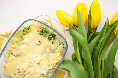 黄郁金香背景下的西兰花奶酪和奶油砂锅图片