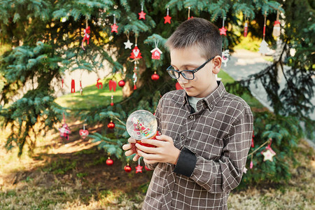 圣诞树附近有玻璃雪球的男孩7月圣诞图片