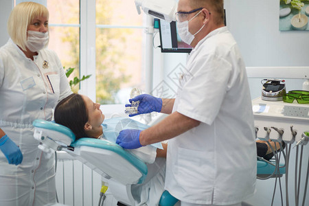 医生牙医治疗一个美丽的年轻女孩病人的牙齿牙医接待处的女孩牙医图片