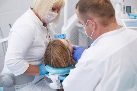 医生牙医治疗一个美丽的年轻女孩病人的牙齿牙医接待处的女孩牙医图片