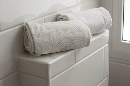 两条滚动白毛巾躺在旅馆温泉疗养所浴室的洗手间图片