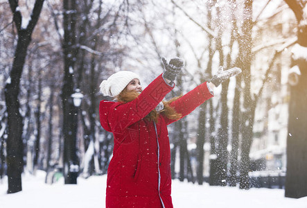 年轻快乐的红发女人在冬季公园玩雪图片