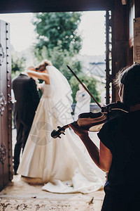 美丽的新娘和新郎在结婚后站在教堂里拉小提琴的音乐家图片