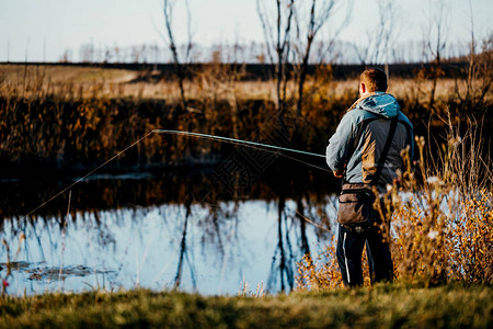 一个男子渔夫在河里钓鱼用一根鱼竿图片