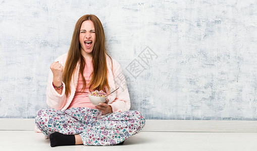年轻的caucasian年轻女人拿着麦片碗欢呼图片