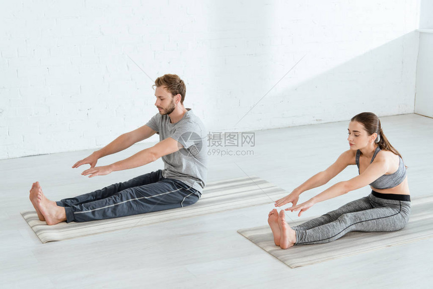 年轻男女在坐姿前屈体式中练习瑜伽图片