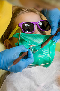 牙医在儿科牙诊所为青春期前的女孩进行牙科填充程序医生使用高速图片