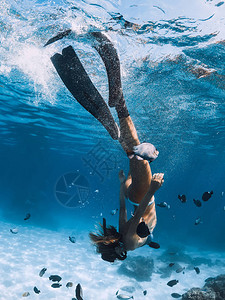 年轻女子在比基尼的滑翔上自由潜水图片