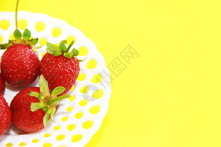 天然红草莓黄底白色装饰板上绿色叶图片