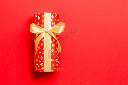 用红色背景上的金丝带用纸包裹圣诞节或其他节日手工制作的礼物图片