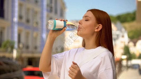 美丽的健康女在城市街道上喝着新鲜的饮用图片