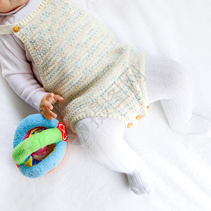 婴儿身体和腿的特写镜头与许多五颜六色的拨浪鼓玩具图片
