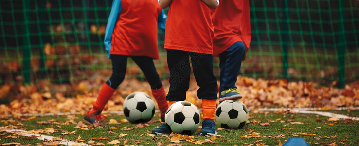 三个男孩在秋季进行足球训练秋季足球户外练习课带球的足球运动员在草地图片
