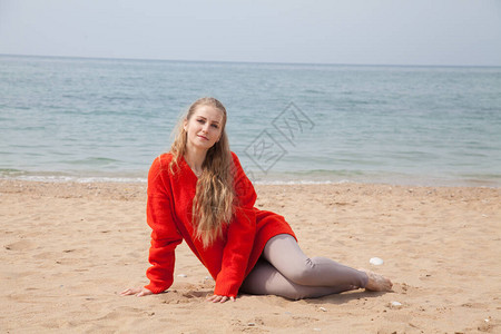 美丽的女人坐在沙滩上在海边图片