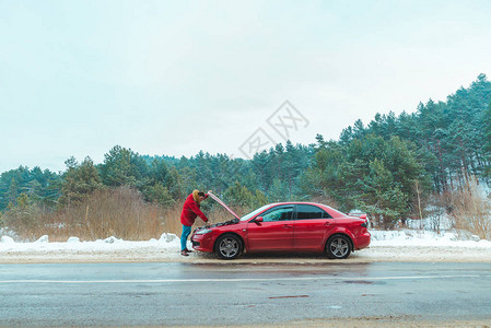 男子站在路边冬季天气下雪的破车附图片