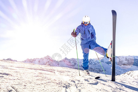 日落时穿着蓝色制服的年轻滑雪者在法国阿尔卑斯山滑雪胜地放松时刻图片