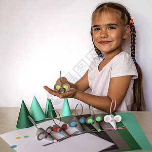 可爱的78岁小女孩用彩色纸和装饰打孔器制作手工老鼠背景图片