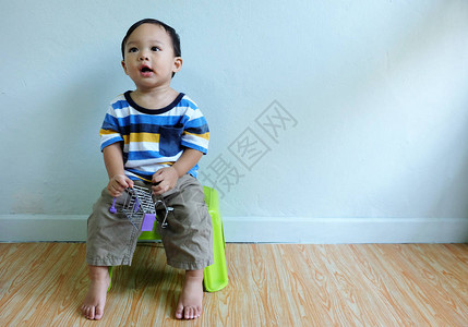 快乐可爱的亚洲男孩正穿着多彩的衬衫坐在椅子上图片