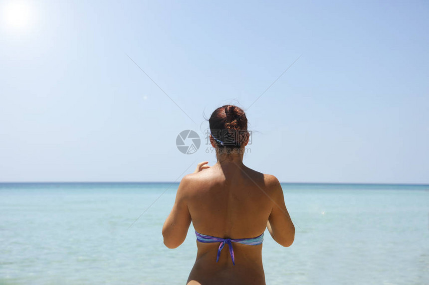 美丽的女人站在海前的背影也许她在看你的智能手机夏日风情美丽图片